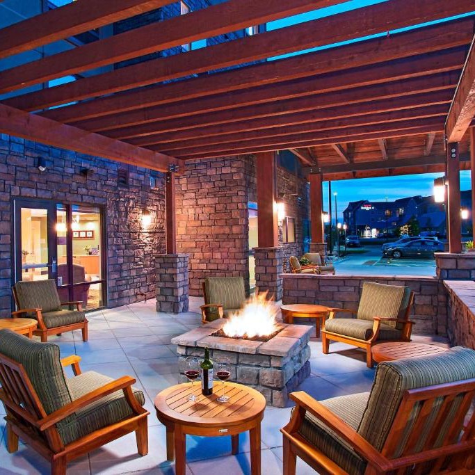 a patio with a fire pit and chairs