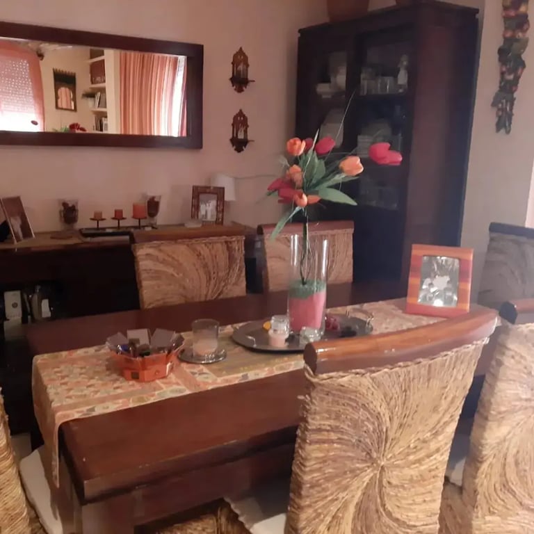 mesa de madera con cuatro sillas de madera una comoda y un espejo