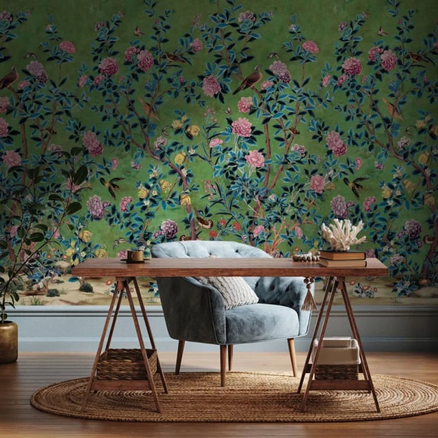 Vintage style floral chinoiserie wallpaper in a home office with a blue armchair and wooden desk.