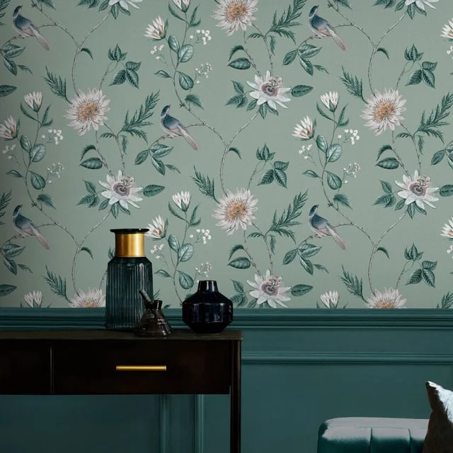 Vintage floral wallpaper with birds and white flowers on a sage green background above dark teal wainscoting.