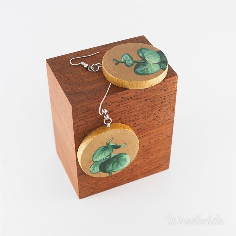 wooden earrings hand painted with leaves motif, displayed on wooden cube