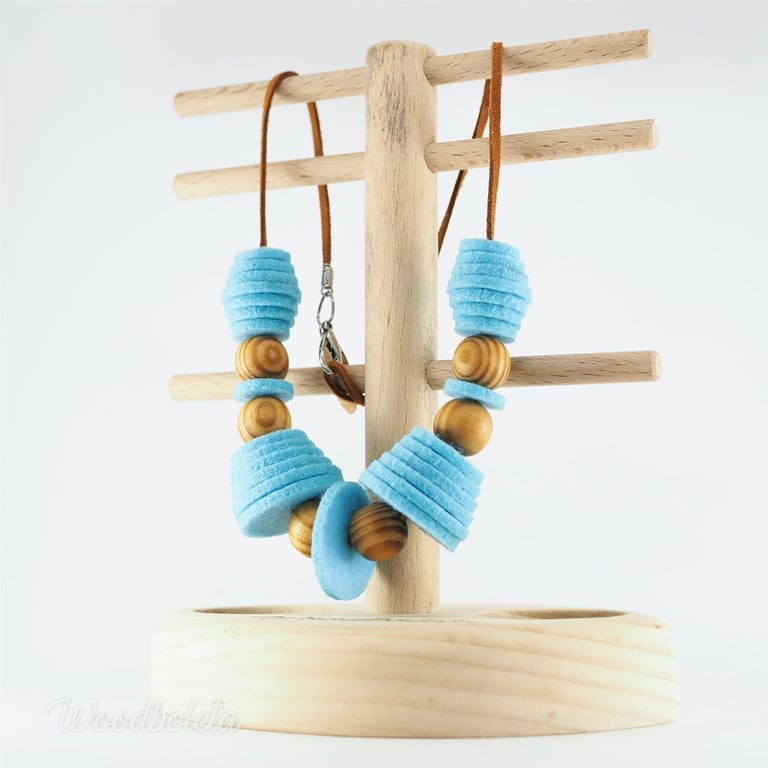 necklace made from blue felt circles and wooden beads, on wooden stand