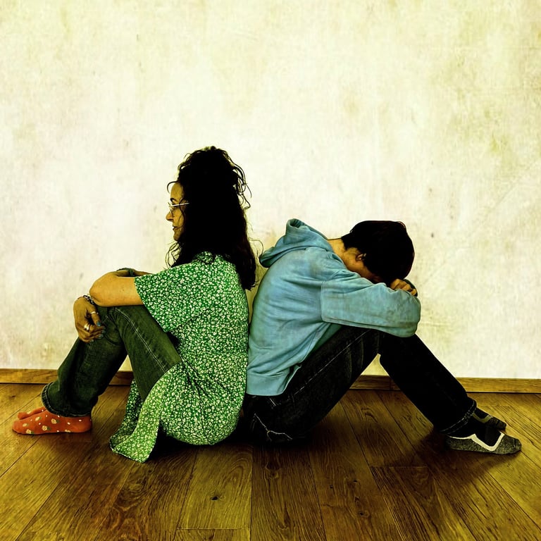 a man and woman sitting back to back on the floor