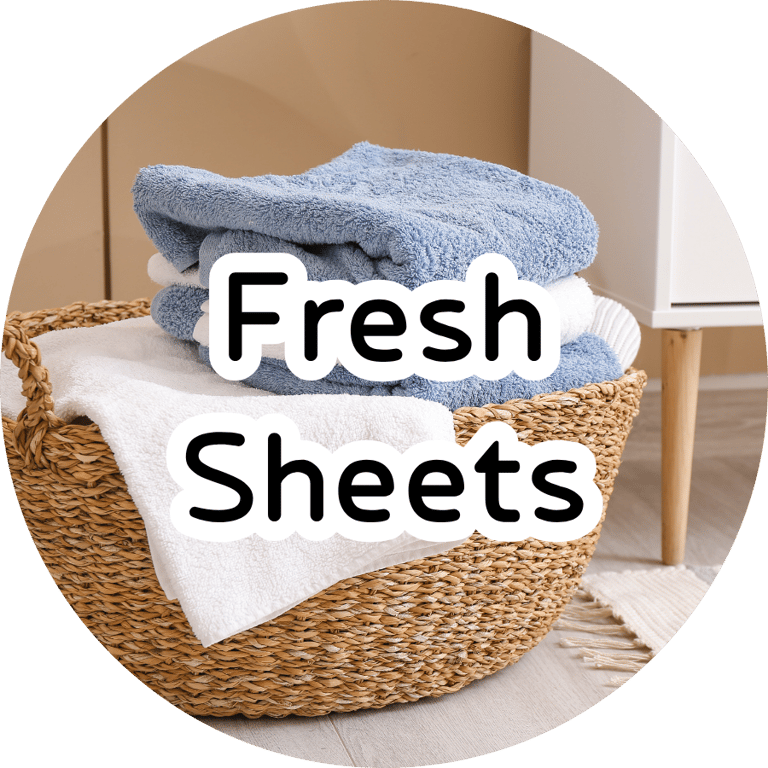 Woven laundry basket with folded blue and white towels and bold overlay text reading "Fresh Sheets." Clean laundry aesthetic.