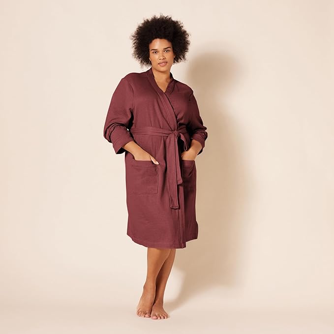 Plus size woman wearing a burgundy waffle knit robe with a tie-waist and front pockets.