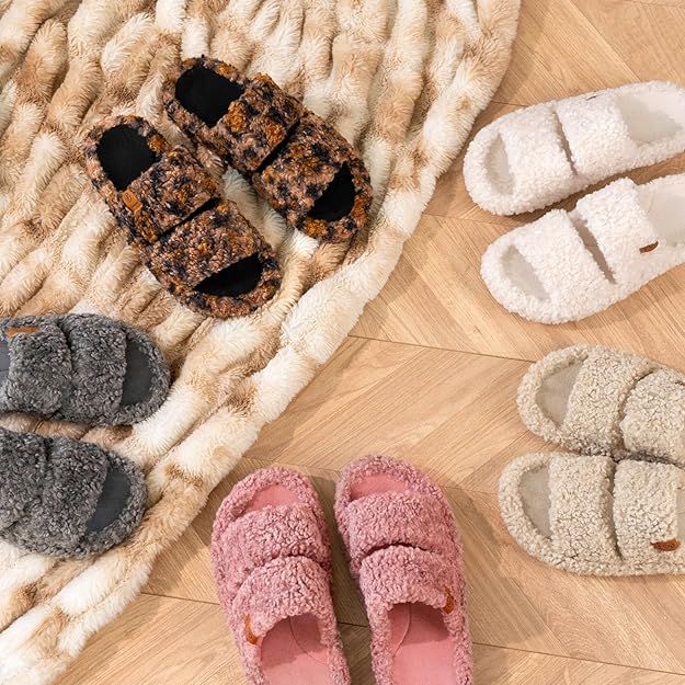 Cozy fuzzy slides for women in various colors and patterns displayed on a plush rug and wood floor.