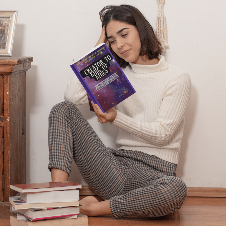 Girl sitting on floor reading Creator To King of Kings bible study 