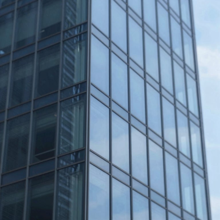 Macro shot of a glass building facade reflecting the blue sky, emphasizing transparency and scale.