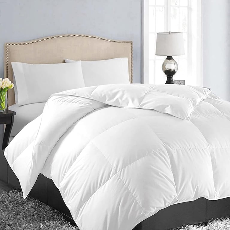 White plush down alternative comforter on a bed with a beige tufted headboard and white pillows.