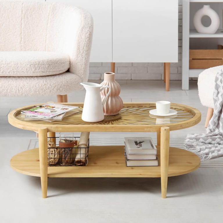 Modern bamboo oval coffee table with a glass top and storage shelf in a bright living room.