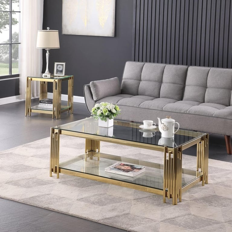 Modern gold glass coffee table and matching end table set in a living room with a grey tufted sofa.