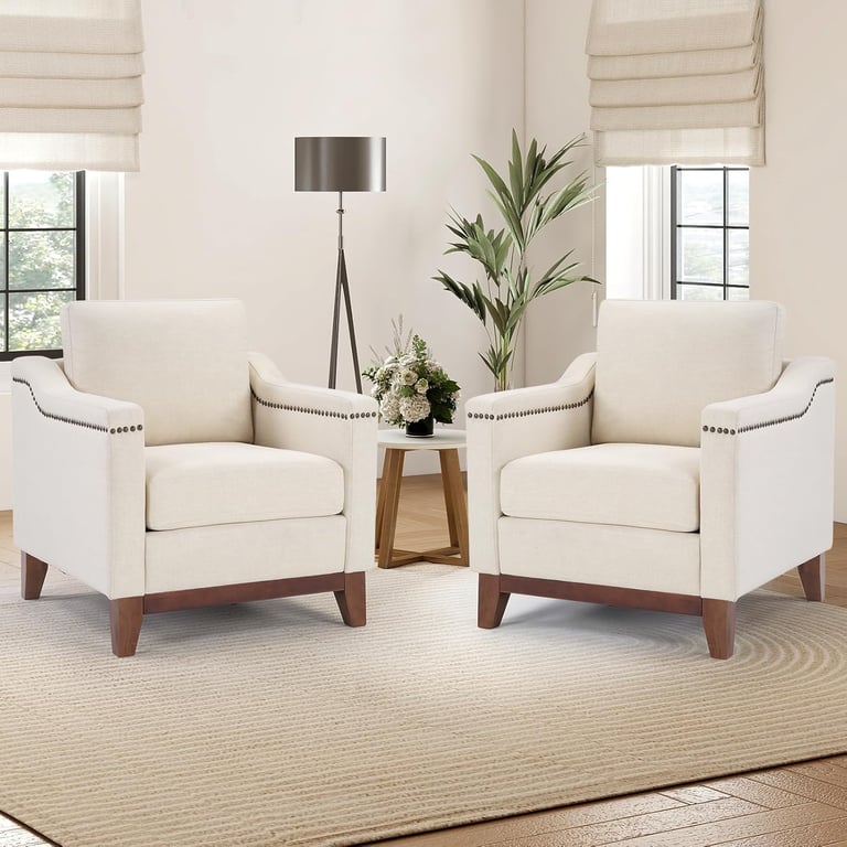 Pair of cream upholstered accent chairs with nailhead trim in a modern living room setting.