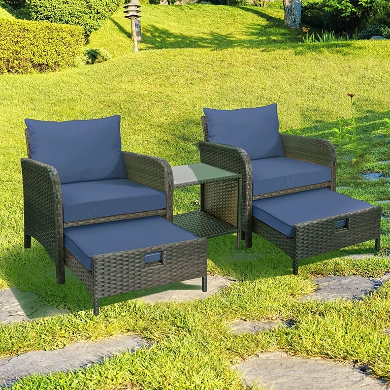 Outdoor 3-piece wicker patio set with blue cushions, two chairs, ottomans, and a side table on a sunny lawn.