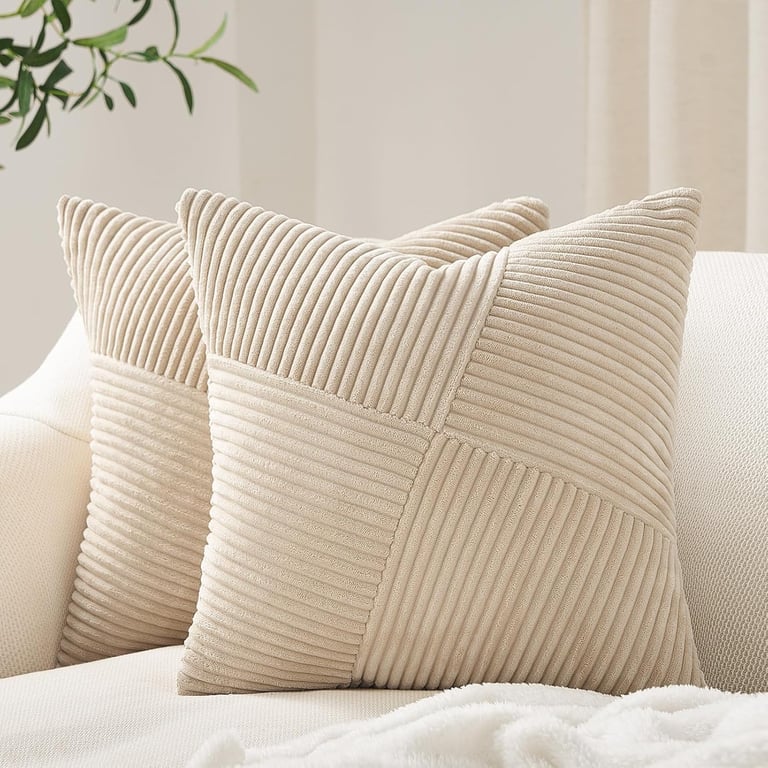 Two beige corduroy decorative throw pillows with a geometric striped pattern on a white sofa.