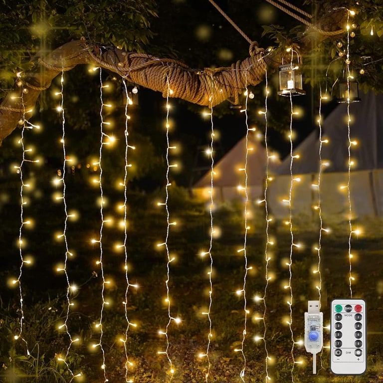 Warm white hanging curtain fairy lights draped from a tree branch in a garden with remote control.