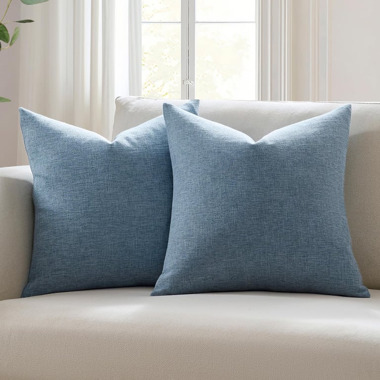 Pair of blue textured decorative throw pillows on a neutral sofa in a bright living room.