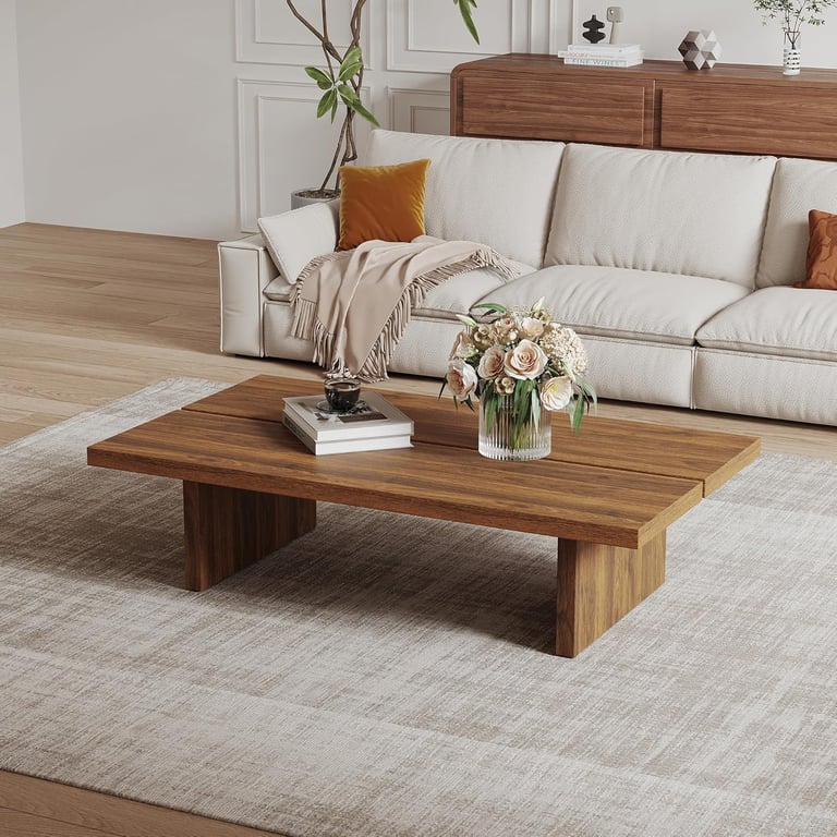 Modern solid wood coffee table on a neutral rug in a minimalist living room with a white sofa.