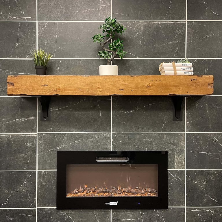 Rustic wood fireplace mantel shelf mounted on a dark grey marble tile wall above a modern electric fireplace.