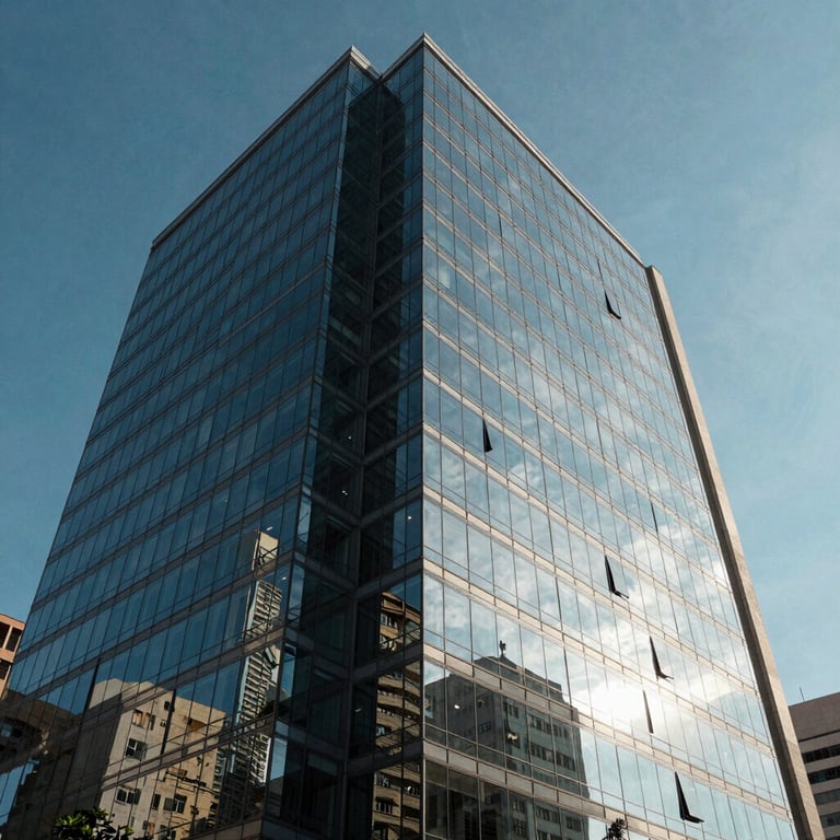 A modern office building exterior in Brazil with glass panels reflecting a clear blue sky, emphasizing structural solidity.