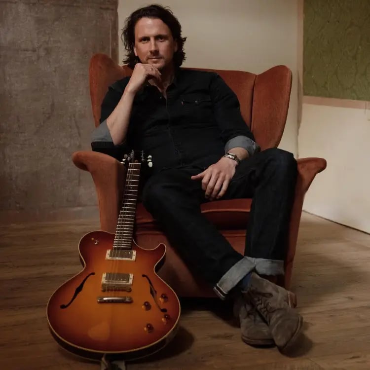 Professional guitarist from Mosaic sitting with a hollow-body electric guitar for an acoustic set