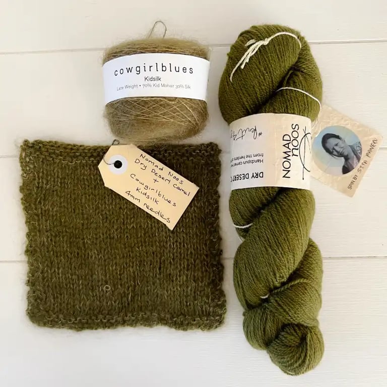 Green yarns and a square of knitting on a white table at Paddock and Purl Studio