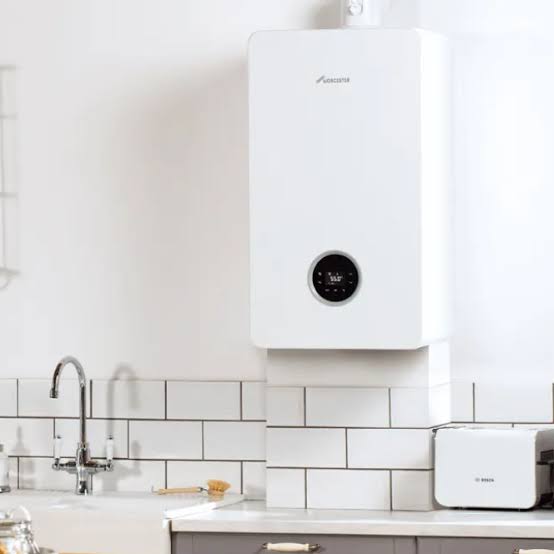 Modern white wall-mounted combi boiler installed in a bright kitchen.