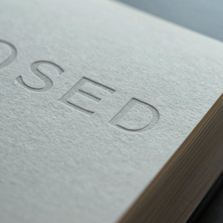 Extreme close-up macro crop of premium textured paper packaging with subtle embossed typography under cool overcast light.