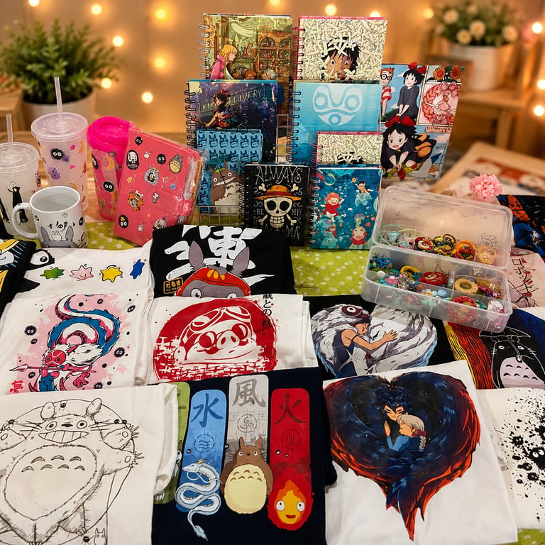 Colección de productos de Studio Ghibli que incluye playeras de Totoro, libretas de anime  en un baz