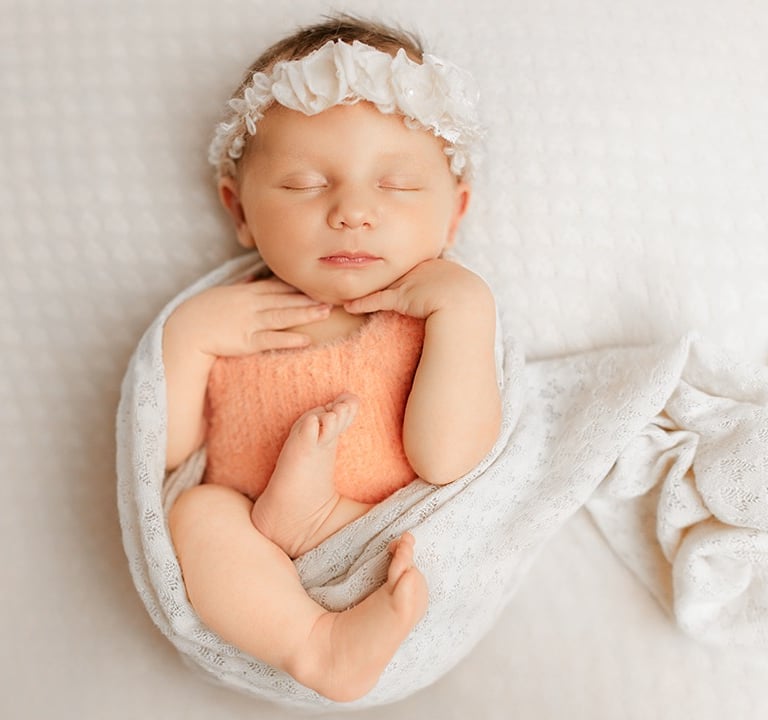 bébé qui dort enroulé d'un wrap de coeurs en rond