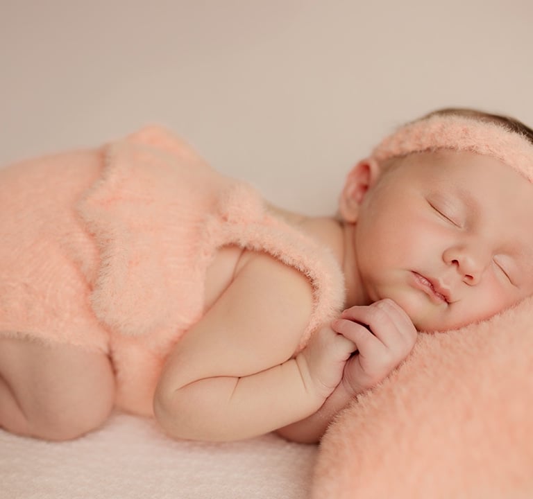 bébé qui dort avec ses petites mains contre sa t^ête