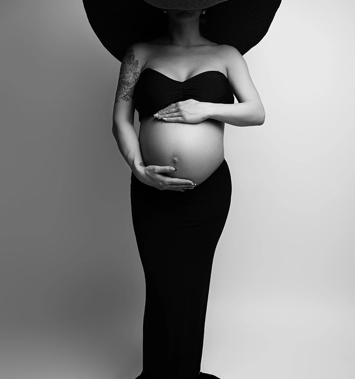 photo maternité comme une oeuvre d'art, portant une longue jupe noire, un grand chapeau noir et son ventre visible