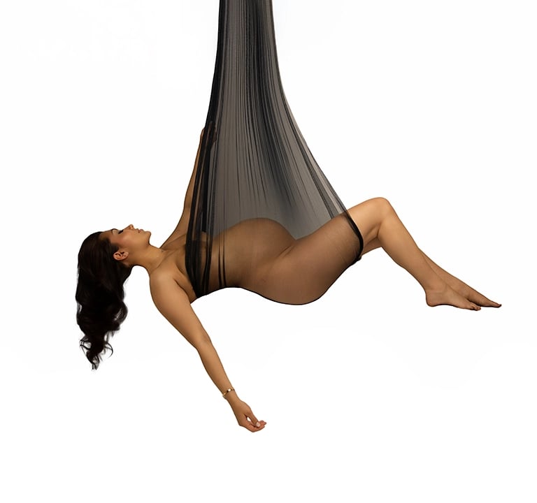 photo de femme enceinte suspendue dans l'air par un voile de tulle noire