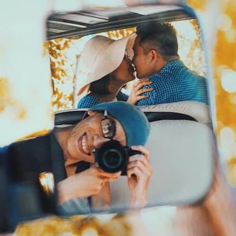 a man and woman kissing in a car mirror