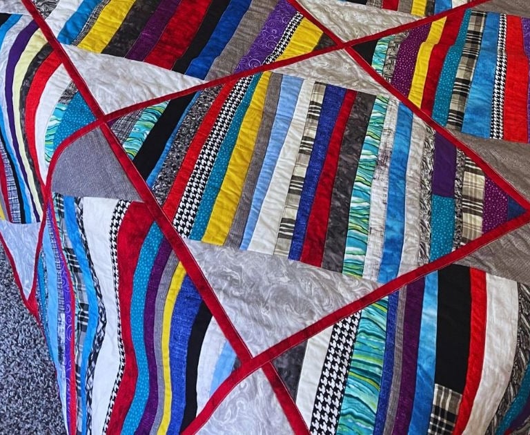 colorful quilt with red sashes and multicolored strips made for my son