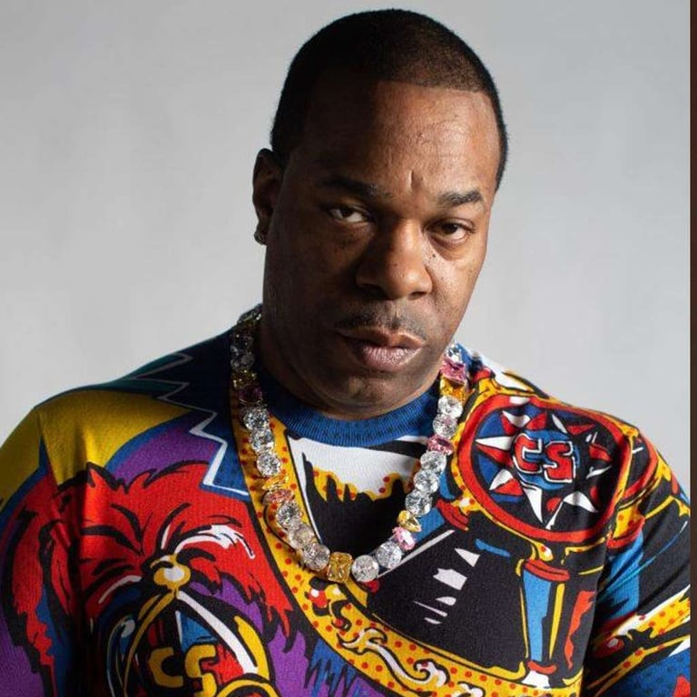 Portrait of rapper Busta Rhymes wearing a colorful graphic sweater and a diamond chain.