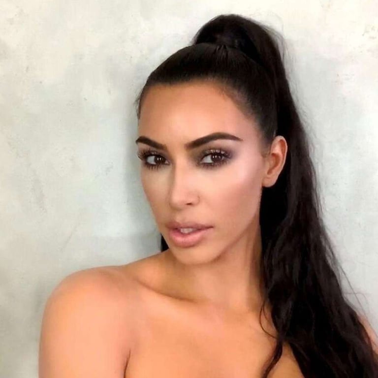 Kim Kardashian posing with a high sleek ponytail and glamorous smokey eye makeup look.