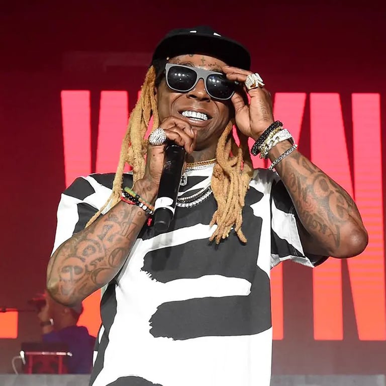 Rapper Lil Wayne performing on stage with a microphone, wearing sunglasses and a black and white shirt.