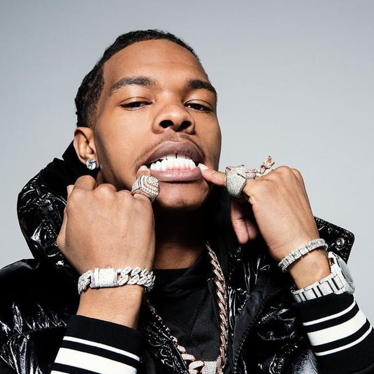 Rapper Lil Baby wearing diamond grillz, heavy gold chains, and luxury jewelry.