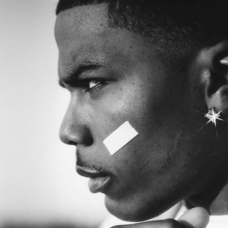 Black and white profile portrait of Nelly featuring his signature face band-aid and diamond earring.