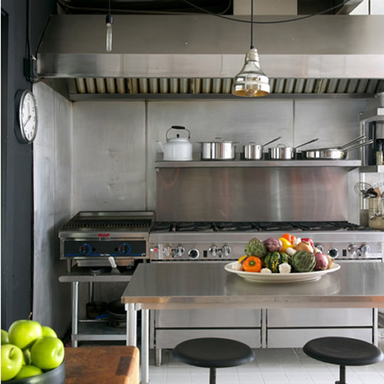 Commercial kitchen with professional range, hood, and Stainless Steel Benchtops in focus.