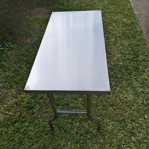 Table Hire: Portable stainless steel folding table on grass, perfect for outdoor events.