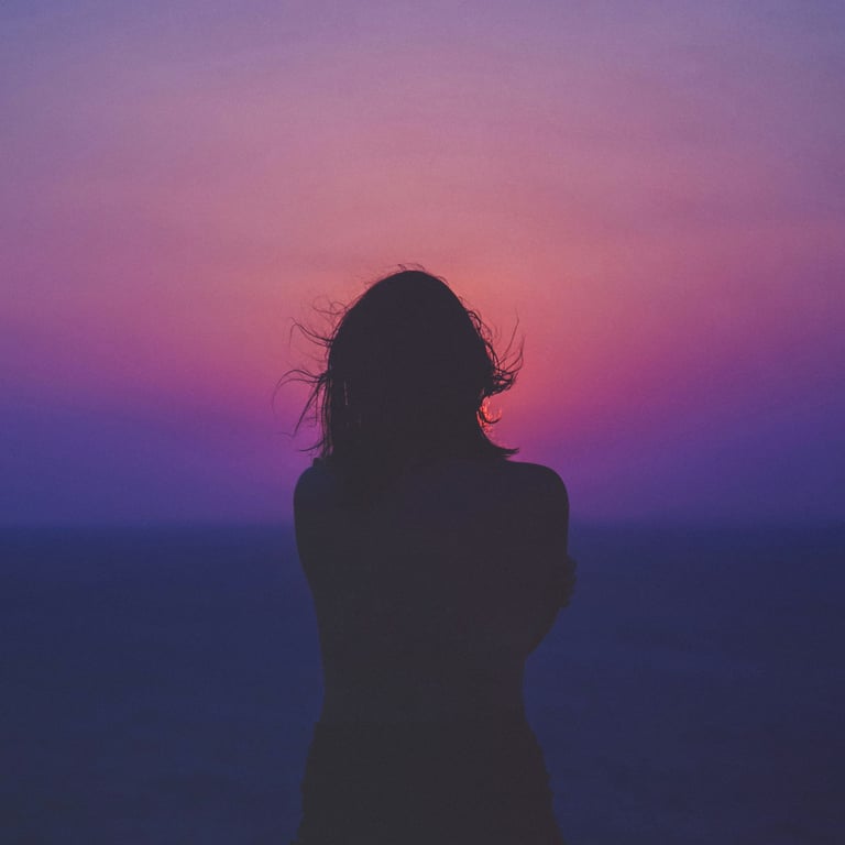 a woman standing in front of a sunset