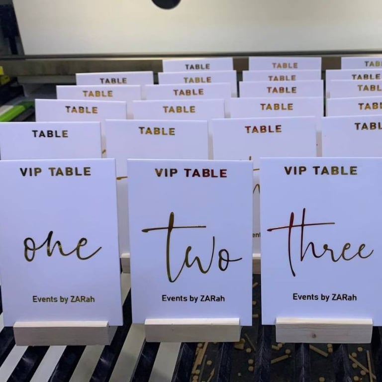 Assorted white Acrylic Table Numbers with black and gold script, labeled from 'one' to 'four' 
