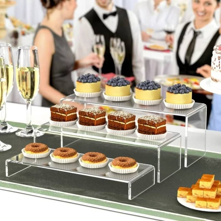 Acrylic risers with a selection of desserts, adding elegance to a catered event setup.