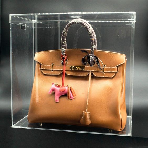 Brown luxury bag in a transparent acrylic case.
