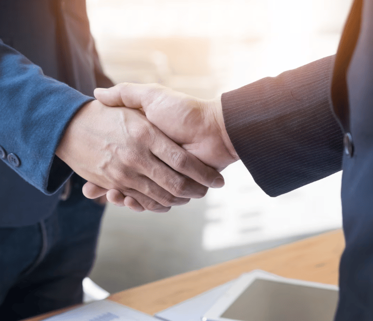 two people shaking hands with a laptop