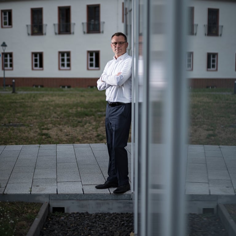 Businessportrait eines Unternehmers in Oranienburg mit verschränkten Armen vor moderner Architektur