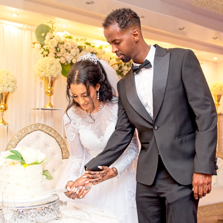 bride in white wedding dress & groom in black suit cutting white wedding cake, light & airy photo