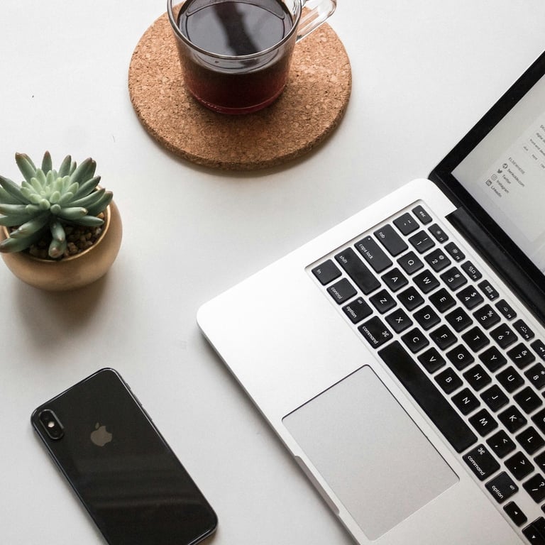 MacBook computer with cup of coffee and a cactus on an office desk