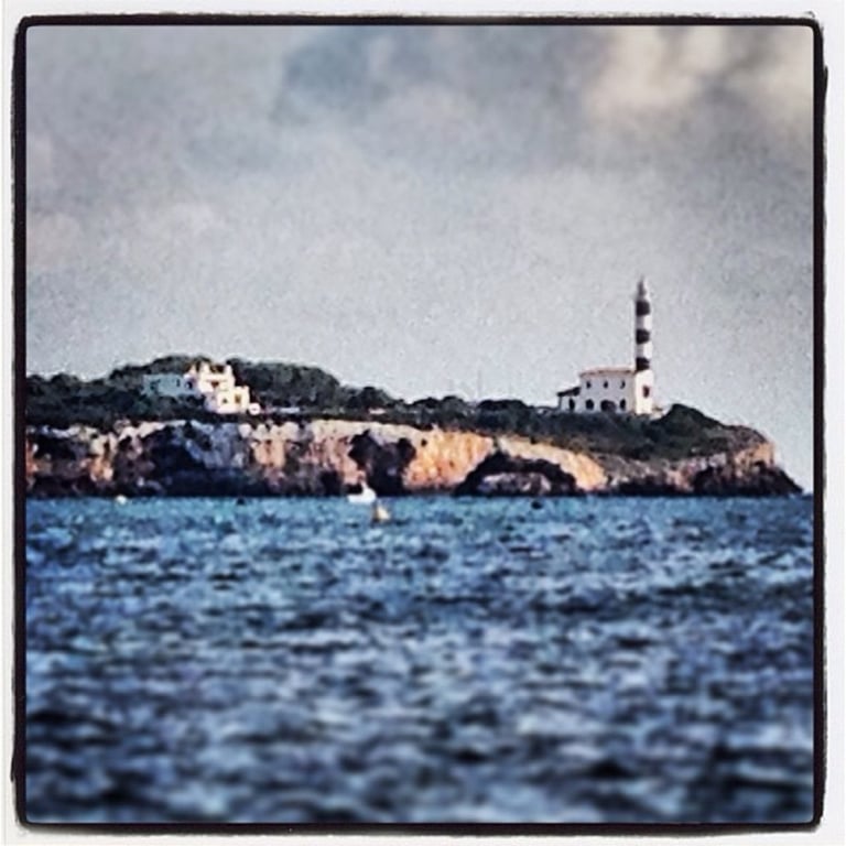 a lighthouse on a rocky island with a lighthouse in the background